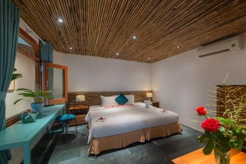 a bedroom with a large bed with a desk and roses at Maple Hotel & Apartment in Nha Trang