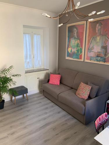 a living room with a couch and paintings on the wall at Casa Flavia-Residenza nel cuore di Ariccia in Ariccia