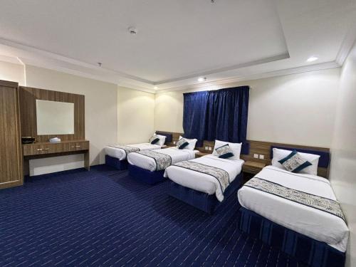 a hotel room with four beds and a mirror at درة الجوار in Al ‘Azīzīyah