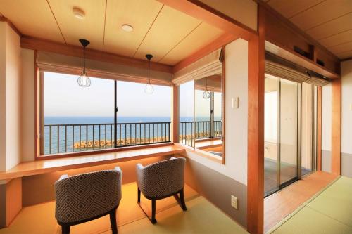 a room with a balcony with a view of the ocean at Yukibou Hakusen in Yonago