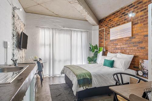 a bedroom with a bed and a brick wall at Views From The 214 in Johannesburg