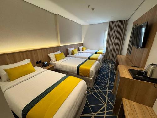 a hotel room with three beds and a television at فندق كرم مضياف Karam Medyaf Hotel in Al Khansāk