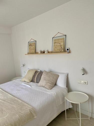 a white bedroom with a bed and a table at Apartamento M Garaje Playa Golf in Zarautz