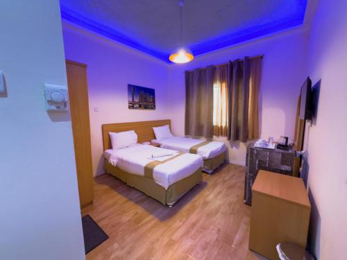 a hotel room with two beds and a television at Sama Hotel in Sharjah