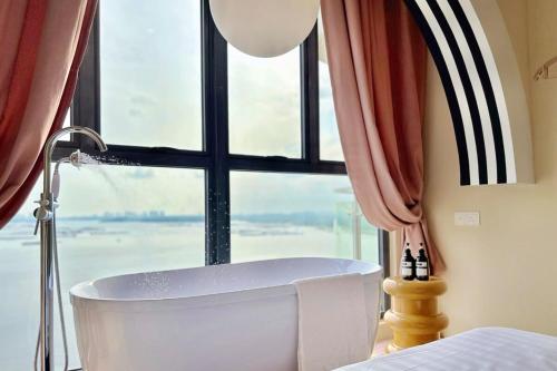 La salle de bains est pourvue d'une baignoire devant une fenêtre. dans l'établissement Dooga Ins-Retro Dreamland Seaview Bathtub by Doogahome Homestay, à Johor Bahru