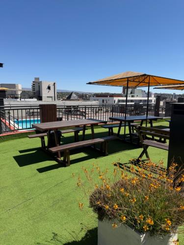 two picnic tables with an umbrella on a roof at Depto Céntrico, Cochera, Pile, Terraza in Villa Carlos Paz