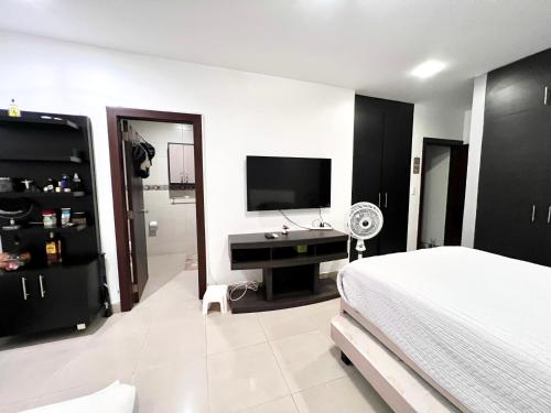 a bedroom with a bed and a flat screen tv at Samborondón Luxury Room by Adriana in SamborondÃ³n