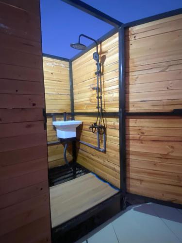 a bathroom with a sink in a wooden wall at Sahara Dream Camp in Al Raka
