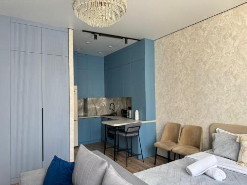 a living room with blue walls and a kitchen at Astana Design Nest in Taldykolʼ