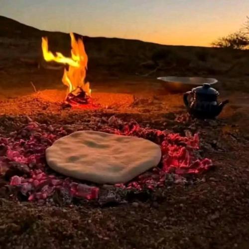 a fire pit with a pie on top of it at Camp Golden Desert Morocco in Mhamid