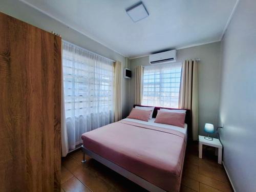 a small bedroom with a bed and two pink pillows at Leaves Apartments in Paramaribo