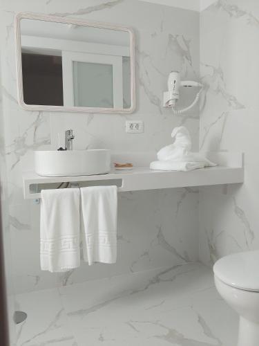 a white bathroom with a sink and a mirror at Hotel Monopol in Puerto de la Cruz