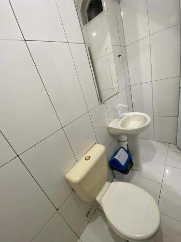 a white bathroom with a toilet and a sink at Hotel Pompéia em Almeirim in Almeirim