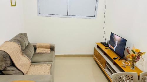 a living room with a couch and a flat screen tv at 1403 Apto 2 Qtos Cabedelo João Pessoa in Ilha da Restinga
