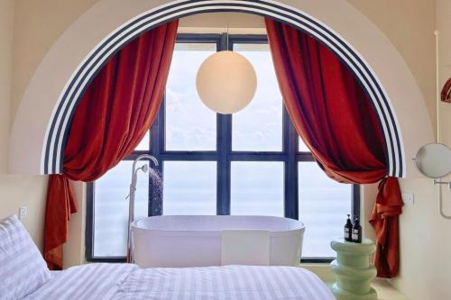 a bedroom with a tub in front of a window at Dooga Ins-Retro Wonderland Seaview Bathtub by Doogahome Homestay in Johor Bahru