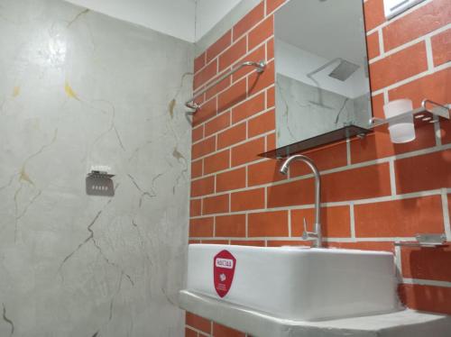 a bathroom with a white sink and a brick wall at The Onisula Guest House in Ahangama