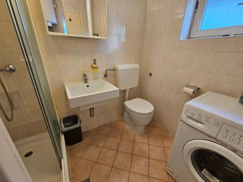 a bathroom with a toilet and a sink and a washing machine at VILLA MEDITERANEA direct at the sea in Novi Vinodolski