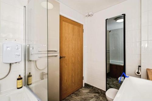 a bathroom with a shower and a wooden door at South Downs Retreat in Sompting