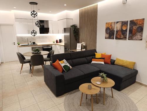Una sala de estar con un sofá negro y una cocina. en Belvedere Luxury Suite, en Tríkala