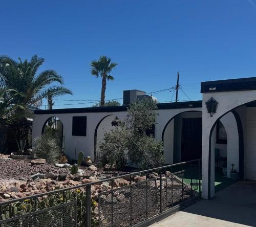 a white house with a fence and palm trees at Entire Vacation home blocks to the Strip, ARTS Dist, & Main Street Sleeps up to 8 in Las Vegas