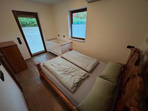 a small bedroom with a bed and two windows at Ferienhaus mit Schwimmbad, Whirlpool & Sauna am Nürburgring in Leimbach