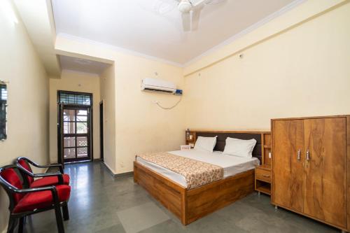 AyodhyaOmji Kathiya Mandir - 2km from Ram Temple的一间卧室，有一张床和一把红椅子