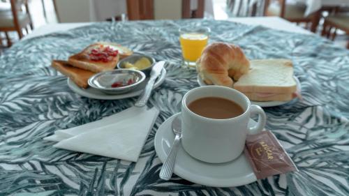 una mesa cubierta con una taza de café y pan en Hotel Che Roga, en Puerto Eldorado