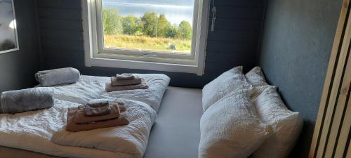 a bedroom with a bed with pillows and a window at Arctic Cabin - Mellomgaard on southern Kvaløya #sauna & bbq hut on site! in Tromsø
