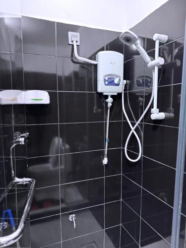 a shower in a black tiled bathroom with a blow dryer at Mody Haven in Kampala