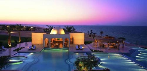a building with a swimming pool in front of the ocean at Azzura Sahl Hasheesh in Hurghada