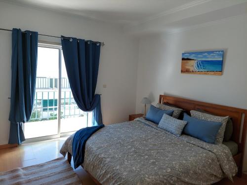 Un dormitorio con una cama con almohadas azules y una ventana. en EncostaOasis Townhouse, en Estibeira