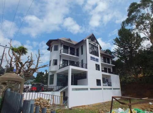 a white building with trees in front of it at Cottage 43 in Nuwara Eliya