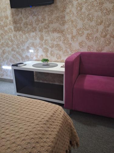 a living room with a purple chair and a table at Garni Hotel Ema in Kragujevac