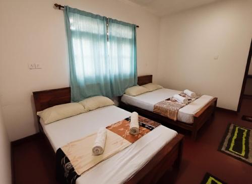 three beds in a room with blue curtains at Willwin Park in Anuradhapura