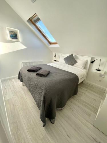 a white bedroom with a large bed with a skylight at Rossnowlagh Waves Lodge in Rossnowlagh