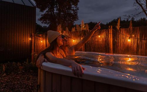 two women sitting in a hot tub at night at Tinyhouse 2 pers met privé hottub in Meerssen