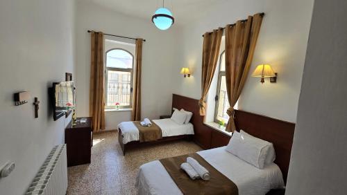een hotelkamer met twee bedden en een raam bij St Thomas Guesthouse - Jerusalem in Jeruzalem