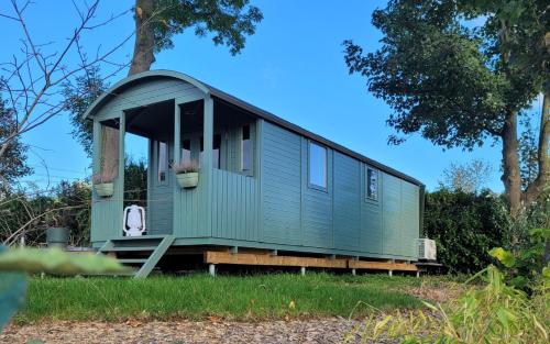 a green tiny house sitting in the grass at Boholodges 2 pers met privé hottub in Meerssen