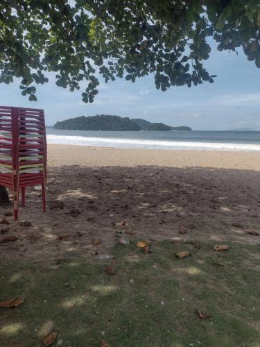 ein roter Stuhl auf einem Strand in der Unterkunft casa da Dora próx da praia in Caraguatatuba