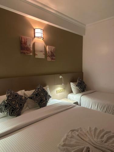 a hotel room with two beds and a light on the wall at The G Ten Holiday Inn in Hulhumale
