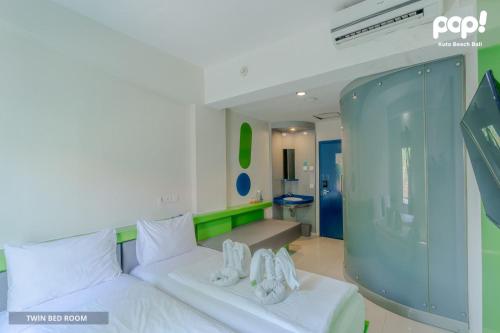 ein Schlafzimmer mit einem weißen Bett mit Schuhen drauf in der Unterkunft POP! Hotel Kuta Beach in Kuta