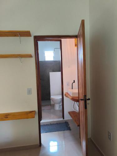 a bathroom with a toilet and a door with a mirror at Kitnets ESPELHO a 160 metros da Praia do Espelho in Praia do Espelho