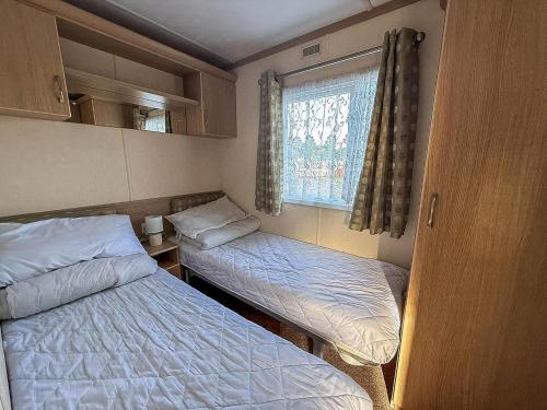 a small room with two beds and a window at Ref 40035Nd - Superb Caravan With Decking & Free Wifi At North Denes Holiday Park in Lowestoft