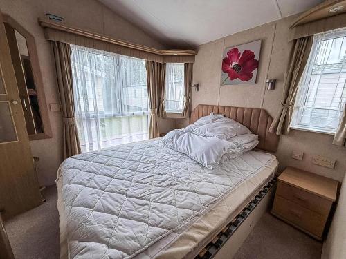a bedroom with a bed with a flower on the wall at Lovely 6 Berth Caravan With Decking At California Cliffs In Scratby Ref 50048L in Great Yarmouth