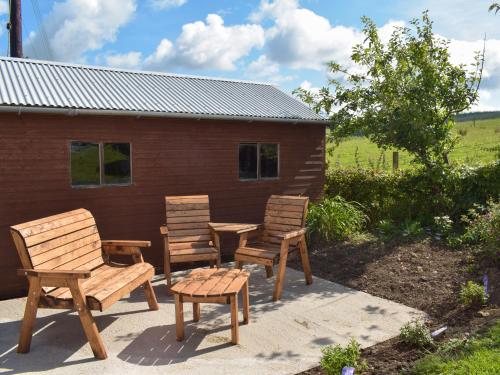 a patio with three chairs and a table and a building at Lilybank Cottage in Doularg