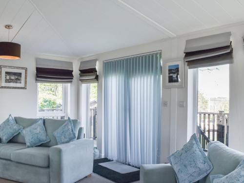 Una sala de estar con un sofá y algunas ventanas. en Sunshine Lodge, en Polperro