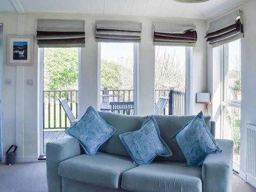 Sofá azul en la sala de estar con ventanas en Sunshine Lodge, en Polperro