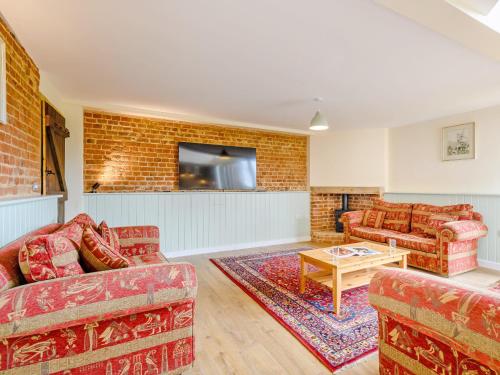 een woonkamer met 2 banken en een bakstenen muur bij Fred's Barn in Swanton Abbot