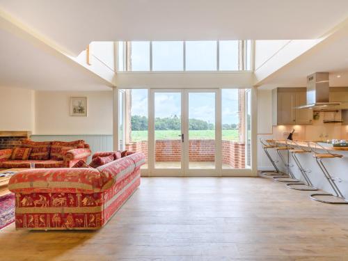 een woonkamer met een bank en een groot raam bij Fred's Barn in Swanton Abbot