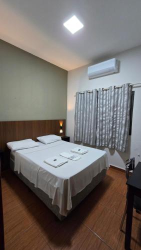 a bedroom with a bed with white sheets and a window at Hotel Barretos Express in Barretos